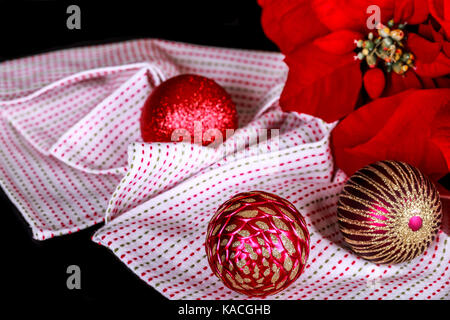 Décoration de Noël, le poinsettia rouge, boule de noël et tissu sur un fond noir. Banque D'Images