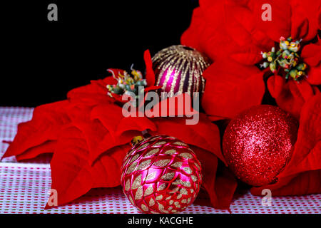 Décoration de Noël, le poinsettia rouge, boule de noël et tissu sur un fond noir. Banque D'Images