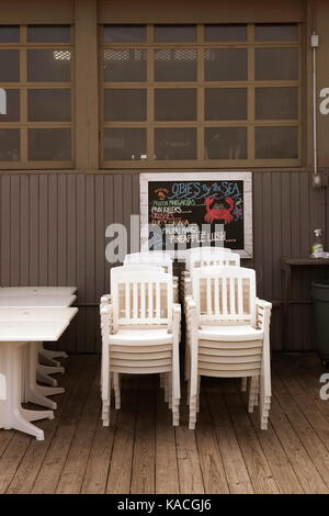 Des chaises en plastique blanc empilés dans un Rehoboth beach, DE, bar, fermé pour la saison morte. Banque D'Images