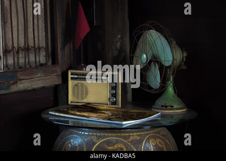 La vie toujours avec des appareils ménagers. Still Life with vieille radio et ventilateur électrique, magazine et bannière avec panneau d'information du conseil. Banque D'Images