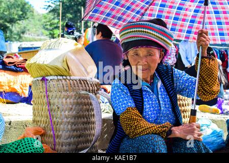 Ha Giang, Vietnam - novembre 08, 2015 : hmong non identifié femme tenant son bébé sur le dos en balade accueil sous le soleil de l'hiver. Banque D'Images