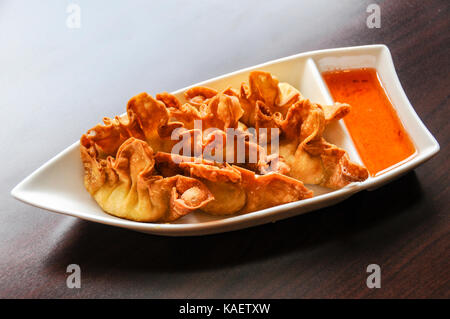 Boulettes de crabe croustillant de Rangoon, rempli d'un mélange de crabe, des châtaignes d'eau, le céleri et le fromage à la crème soyeuse, servi avec sauce aigre-douce. Banque D'Images