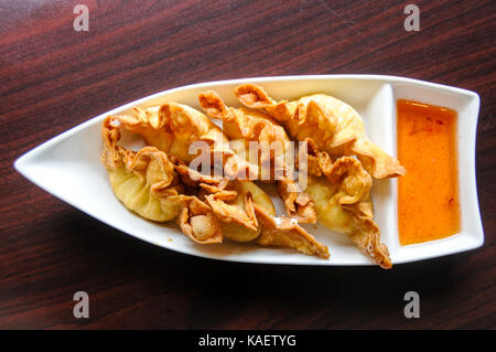 Boulettes de crabe croustillant de Rangoon, rempli d'un mélange de crabe, des châtaignes d'eau, le céleri et le fromage à la crème soyeuse, servi avec sauce aigre-douce. Banque D'Images