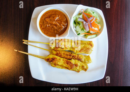 Satay de poulet, poulet mariné grillé sur des brochettes, servi avec sauce aux arachides et salade de concombre. Banque D'Images