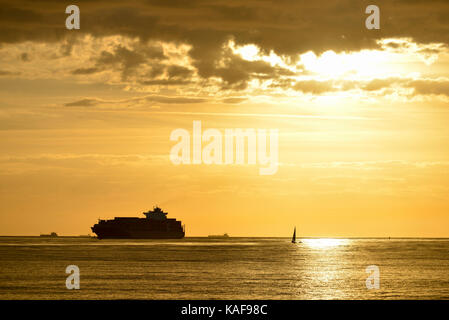 Le Havre (Normandie, région du nord-ouest de la France) : container ship et voilier au large de la côte au coucher du soleil Banque D'Images