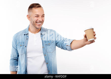 Cheerful young man giving une tasse de café en papier Banque D'Images