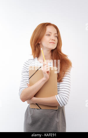 Red-haired woman holding folder et crayon Banque D'Images