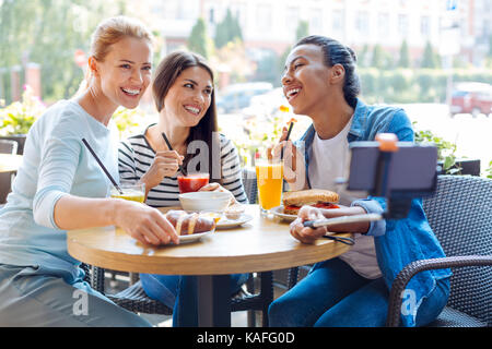 Happy friends prenant en selfies cafe avec stick selfies Banque D'Images