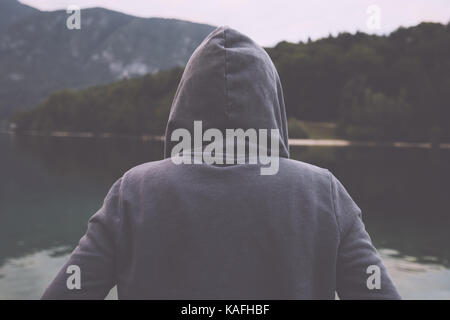 Portrait de nostalgique sombre triste mélancolique solitaire avec des femelles adultes Hooded Jacket debout sur la rive du lac Misty en couvert matin et de penser Banque D'Images