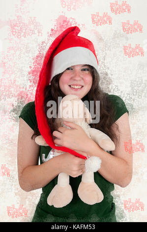 Amélioration de l'image numérique d'une jeune teen wearing Santa's helper hat et serrant un ours en peluche avec ambiance de Noël Banque D'Images