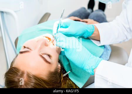 Femme dentiste vérifiant les dents du patient avec accolades au bureau. Clinique dentaire, médecine, dentisterie concept. Equipement dentaire. close up. Banque D'Images