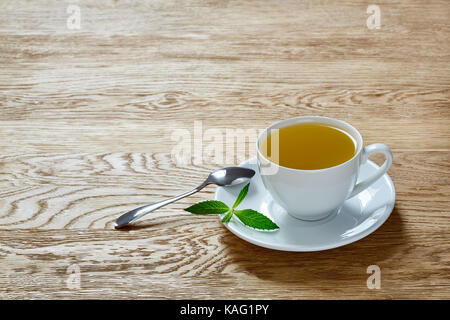 Tasse de thé à la menthe et les feuilles vertes sur table lumineuse Banque D'Images