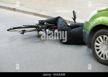 Cycliste homme inconscient allongé sur route après accident de la route Banque D'Images