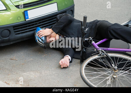 Cycliste homme inconscient allongé sur route après accident de la route Banque D'Images