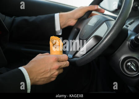 Close-up of a male holding snack en roulant dans sa voiture Banque D'Images