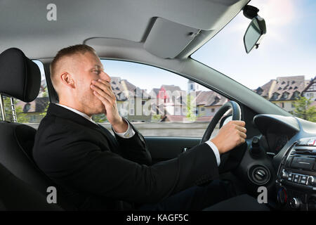 Portrait of a young businessman de bâiller au volant d'un véhicule Banque D'Images