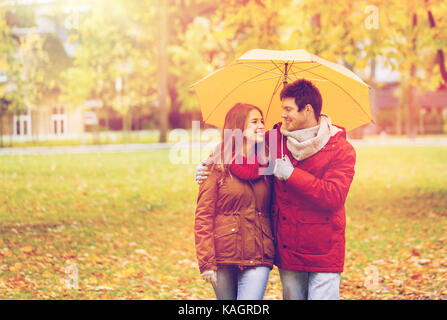 Smiling couple with umbrella in autumn park Banque D'Images