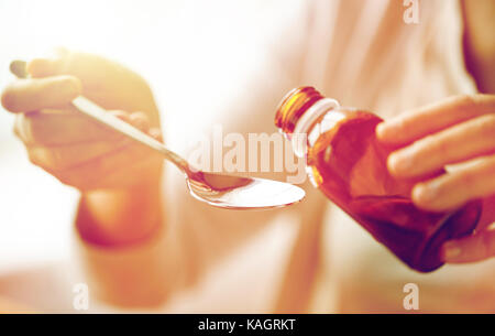 Woman pouring médicament du biberon à la cuillère Banque D'Images