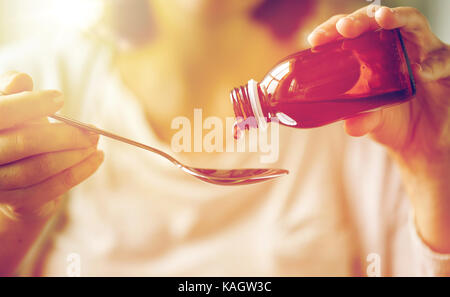 Woman pouring médicament du biberon à la cuillère Banque D'Images