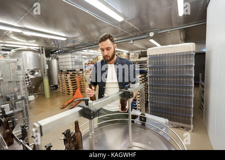 Les hommes avec des bouteilles sur le convoyeur à craft beer brewery Banque D'Images