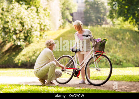 Happy senior couple avec vélo au parc d'été Banque D'Images