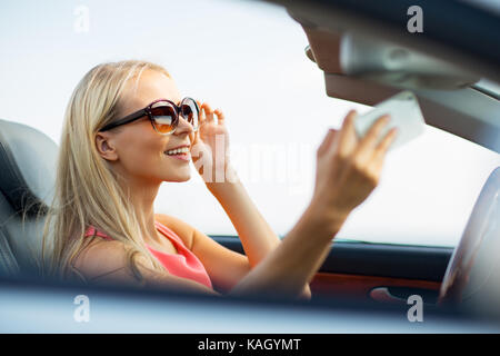 Femme en voiture décapotable selfies en tenant Banque D'Images