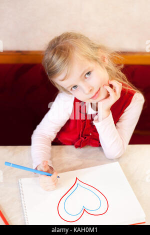 Smiling little girl attire l'coeur dans un album de la Saint-Valentin. Banque D'Images