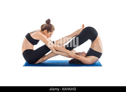 Yoga partenaire isolé sur fond blanc. deux jeunes femmes faisant du yoga asanas. Banque D'Images