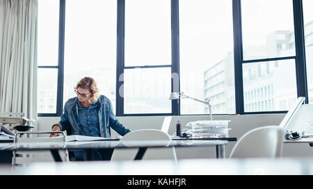 Young businesswoman travaillant à son bureau. Concepteur de femmes travaillant sur blueprint in office. Banque D'Images