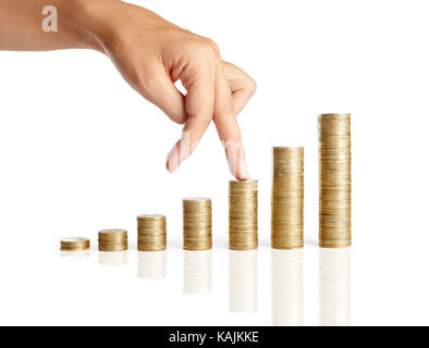 Les doigts à monter sur des piles de pièces de monnaie isolé sur fond blanc. La croissance finances concept Banque D'Images
