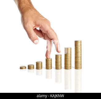 Les doigts à monter sur des piles de pièces de monnaie isolé sur fond blanc. La croissance finances concept Banque D'Images