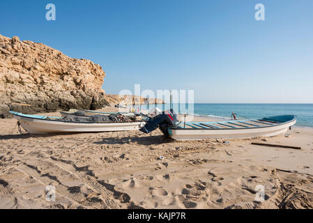 Pêcheurs bateaux sur une plage de Ras Al Jinz, Sultanat d'Oman, avec un ciel bleu clair, des méthodes traditionnelles et la vie quotidienne des communautés côtières Banque D'Images