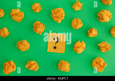 Boules de papier froissé jaune et point d'interrogation sur un fond vert. close up. Banque D'Images