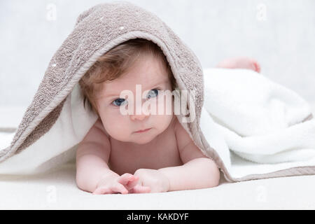 Mignon bébé nouveau-né fille avec de beaux yeux bleus sur un couvre-lit blanc terry. adorable bébé à la recherche dans le cadre d'une couverture blanche ou d'une serviette. triste petite fille en serviette blanche après la douche. Banque D'Images