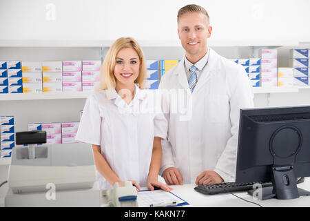 Portrait de l'homme et de la femme les pharmaciens smiling at counter in pharmacy Banque D'Images