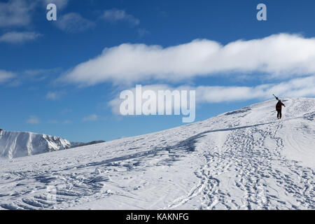 Avec skieur skis sur l'épaule aller jusqu'en haut de la montagne dans le froid soleil jour. Montagnes du Caucase en hiver, la Géorgie, la région Gudauri, Mt. Kudebi. Banque D'Images