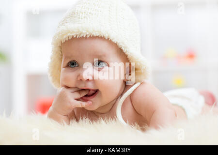 Cute baby girl portée dans white hat sucer ses doigts Banque D'Images