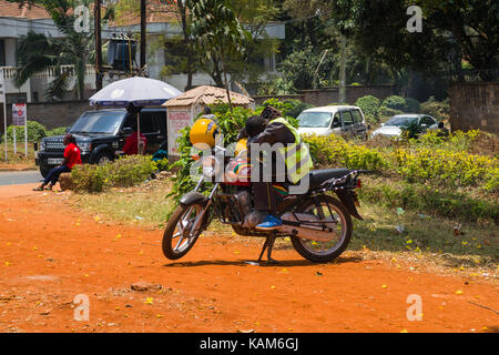 Chauffeur de taxi moto boda boda coin couchage sur moto par le bas-côté de la route, Nairobi, Kenya Banque D'Images