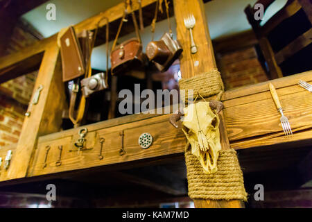 La photo horizontale de la tête de taureau accroché sur l'escalier en bois décoré avec des clés, fourchettes et sacs pour appareils photo numériques dans le café. Banque D'Images