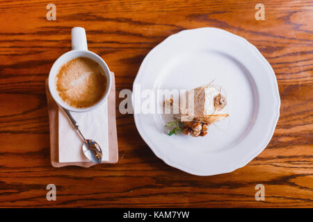 La vue ci-dessus du délicieux dessert décoré de menthe, de noix et d'orange séchée, debout près de la tasse de café d'arome placé sur la table en bois. Banque D'Images