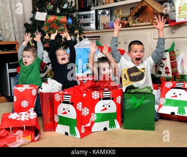Quatre enfants exprimer leur joie et d'excitation de Noël en levant les bras et criaient 'merry christmas'. Ils posent devant l'christm Banque D'Images