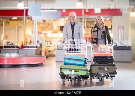 Happy business couple dans des chariots à l'aéroport Banque D'Images