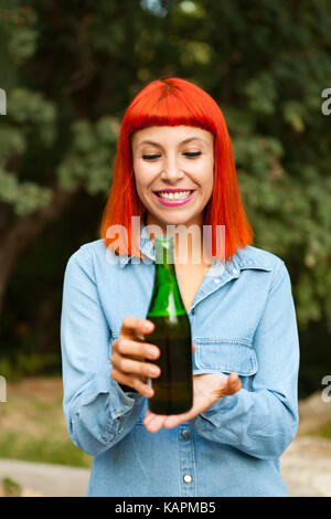 Femme rousse à la campagne le grillage avec une bouteille verte dans la campagne Banque D'Images