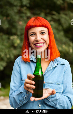 Femme rousse à la campagne le grillage avec une bouteille verte dans la campagne Banque D'Images