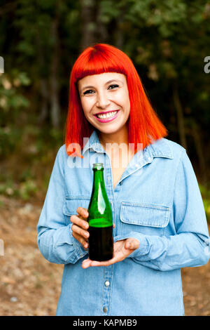 Femme rousse à la campagne le grillage avec une bouteille verte dans la campagne Banque D'Images