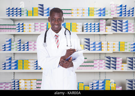 Portrait of male pharmacien writing on clipboard in pharmacy Banque D'Images