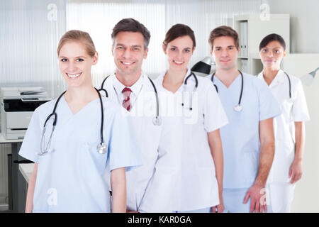 Portrait of smiling male et femelle doctors standing in row at hospital Banque D'Images