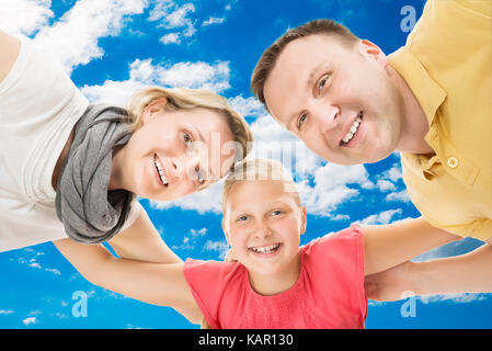 Low angle portrait of happy parents with daughter formant huddle against sky Banque D'Images