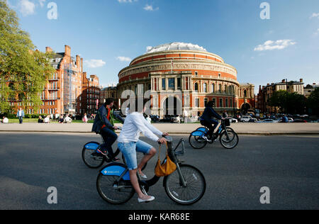 Les touristes en vélo de location en passant par le Royal Albert Hall de Londres. système de partage de vélos lancé avec 6000 vélos sur 2010 pour aider à atténuer la congestion routière Banque D'Images