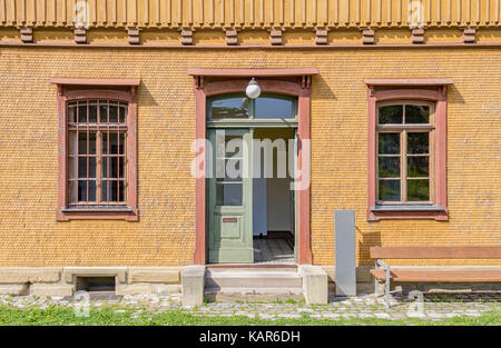 Lambris de bois historique façade de maison avec des barreaux aux fenêtres dans l'ambiance ensoleillée Banque D'Images